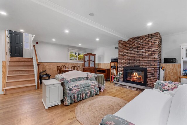 living area featuring light wood-style floors, ornamental molding, wainscoting, and stairway