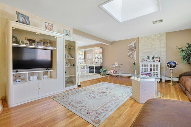 living room featuring a baseboard heating unit, a skylight, visible vents, and wood finished floors