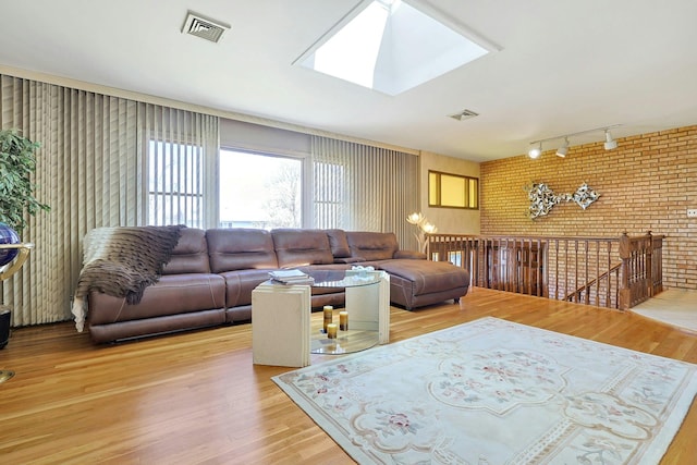 living room with rail lighting, visible vents, a skylight, and light wood-style floors