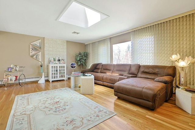 living area featuring a skylight, a baseboard radiator, wood finished floors, and visible vents