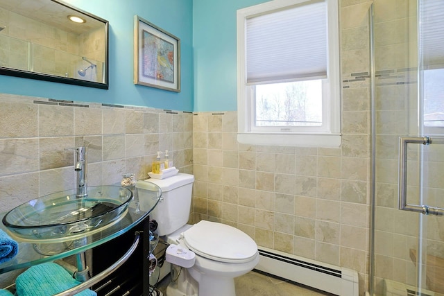 full bathroom with tile walls, a tile shower, a sink, a baseboard heating unit, and toilet