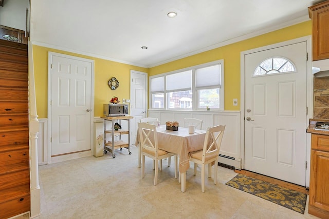 dining room featuring crown molding, a decorative wall, a healthy amount of sunlight, and a wainscoted wall