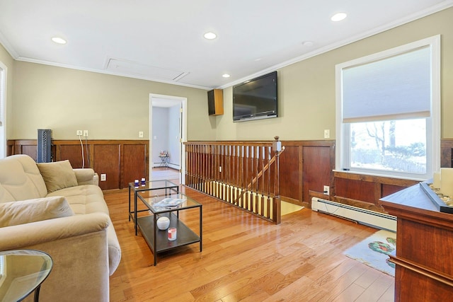 living room featuring wainscoting, ornamental molding, baseboard heating, and attic access