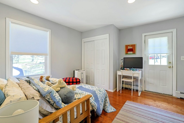bedroom featuring recessed lighting, a closet, baseboard heating, and wood finished floors