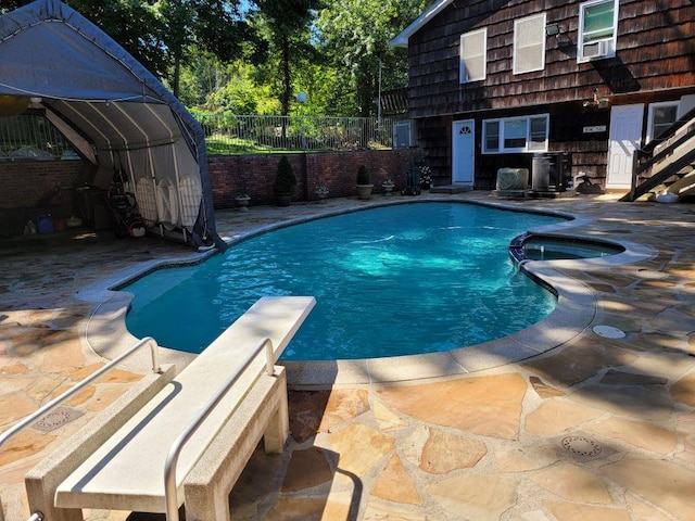 view of pool with a patio, fence, cooling unit, and a diving board