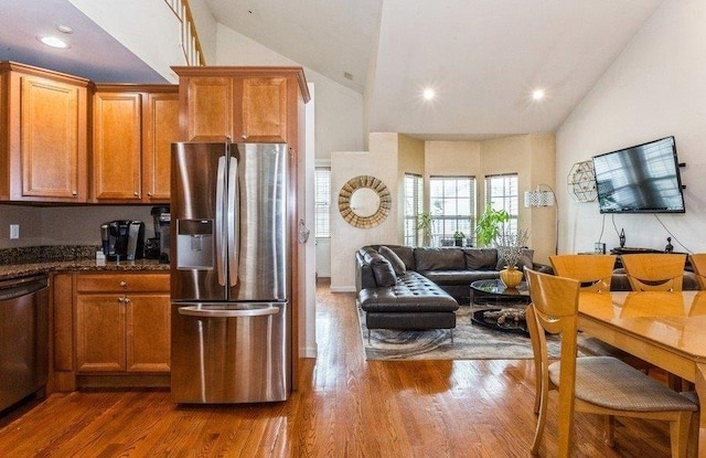 kitchen with brown cabinetry, lofted ceiling, appliances with stainless steel finishes, and dark wood-style floors