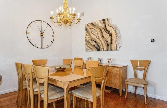 dining room featuring wood finished floors, visible vents, baseboards, and a notable chandelier
