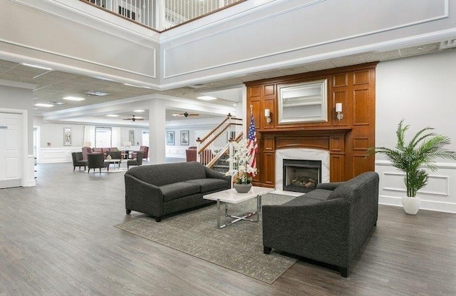 living area with a premium fireplace, wood finished floors, stairs, and a decorative wall