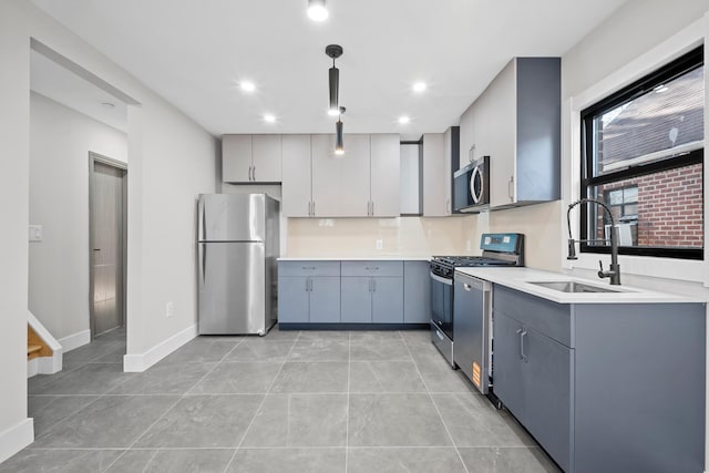 kitchen with a sink, gray cabinetry, light countertops, appliances with stainless steel finishes, and hanging light fixtures