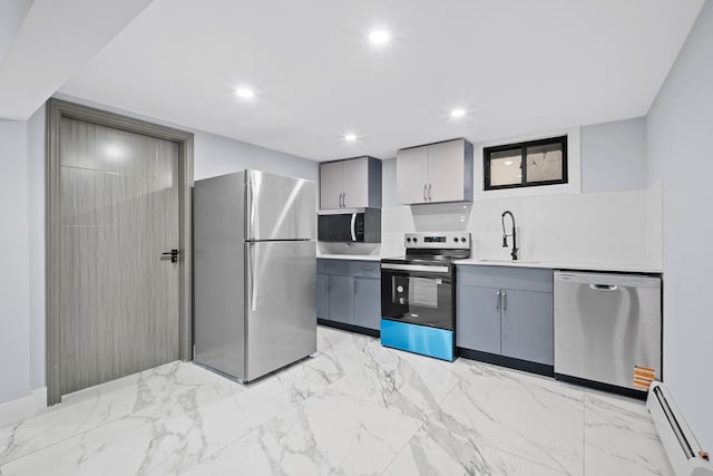 kitchen with a sink, backsplash, appliances with stainless steel finishes, gray cabinets, and a baseboard radiator