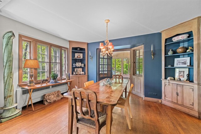 1391 Hunterbrook Rd, Yorktown Heights, NY 10598 - dining space featuring radiator, a chandelier, wood finished floors, and built in shelves