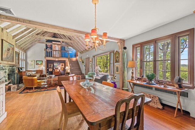 1391 Hunterbrook Rd, Yorktown Heights, NY 10598 - dining space featuring a chandelier, light wood-style floors, stairs, a stone fireplace, and radiator heating unit
