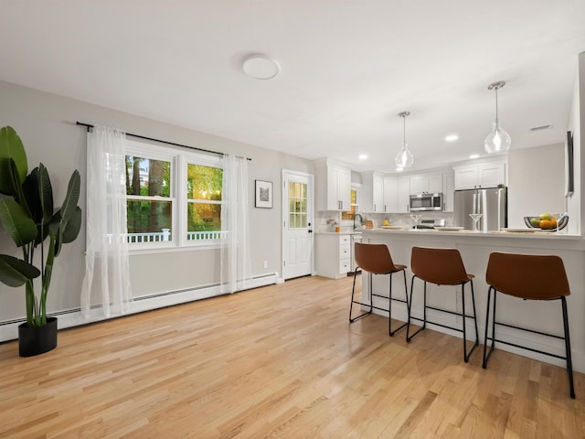 31 Pennsylvania Ave, Valley Cottage, NY 10989 - kitchen featuring appliances with stainless steel finishes, a breakfast bar area, light wood finished floors, white cabinetry, and light countertops
