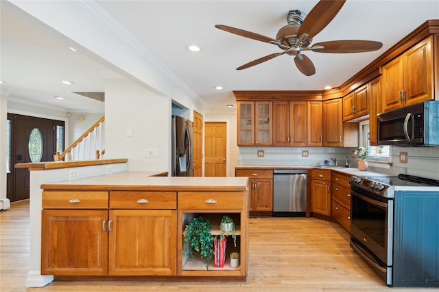 kitchen with light wood-type flooring, crown molding, a peninsula, brown cabinetry, and appliances with stainless steel finishes