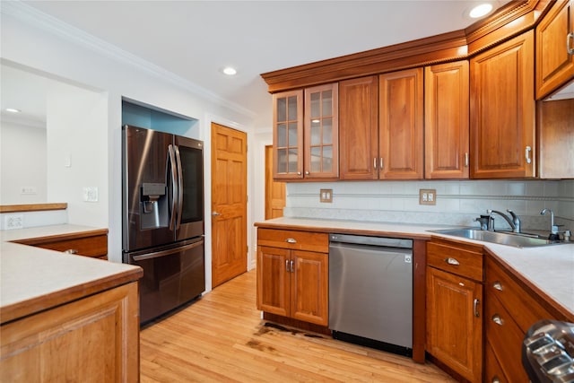 kitchen with crown molding, tasteful backsplash, a sink, brown cabinetry, and stainless steel appliances