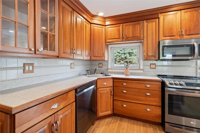 kitchen with brown cabinets, appliances with stainless steel finishes, a sink, and light countertops