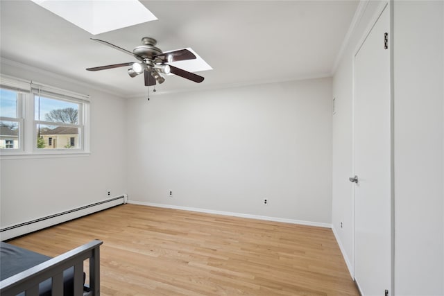 unfurnished bedroom featuring light wood-type flooring, crown molding, a skylight, baseboards, and a baseboard radiator