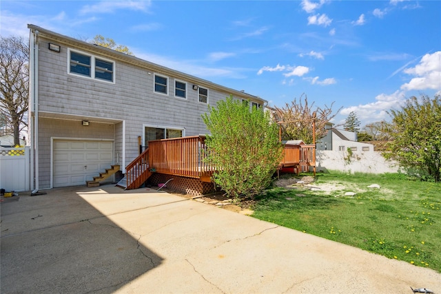 back of property with concrete driveway, a deck, a yard, and a garage