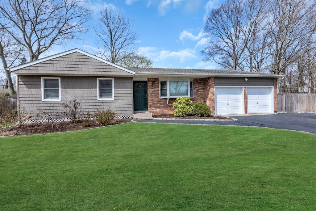 ranch-style house featuring a garage, aphalt driveway, fence, a front yard, and brick siding