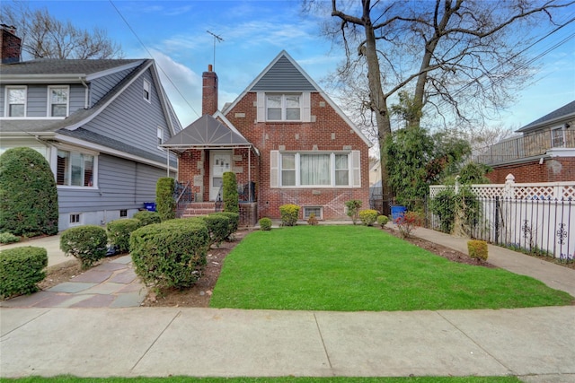 view of front of property featuring brick siding, a chimney, a front yard, and fence
