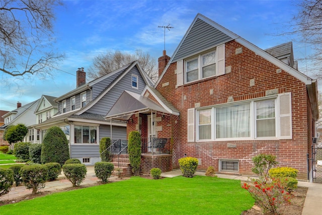bungalow-style home featuring a chimney, brick siding, and a front yard
