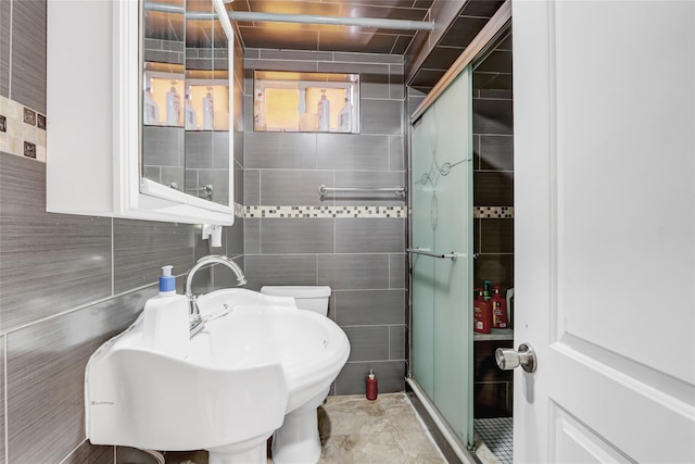 bathroom with a shower stall, tile walls, and a sink