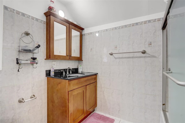 bathroom with a shower with shower door, vaulted ceiling, tile walls, and vanity