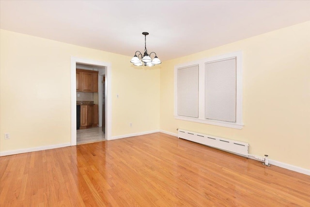 224-40 Fairbury Ave, Queens Village, NY 11428 - spare room featuring baseboards, light wood-style flooring, baseboard heating, and an inviting chandelier