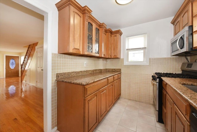 224-40 Fairbury Ave, Queens Village, NY 11428 - kitchen featuring brown cabinets, glass insert cabinets, appliances with stainless steel finishes, and dark stone counters