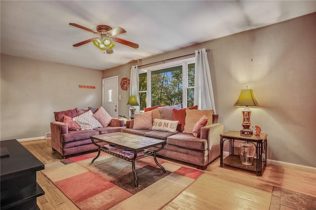 living room with light wood-type flooring, a ceiling fan, and baseboards