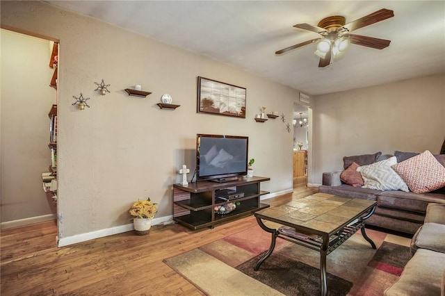 living area with baseboards, a ceiling fan, and wood finished floors
