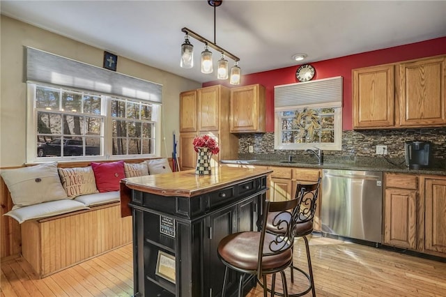 kitchen featuring stainless steel dishwasher, backsplash, and light wood-style floors