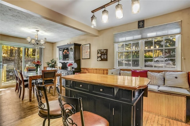 bar with light wood-style flooring, pendant lighting, and a notable chandelier