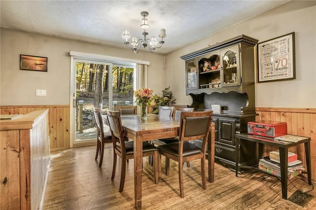 dining space with wooden walls, a textured ceiling, and wainscoting