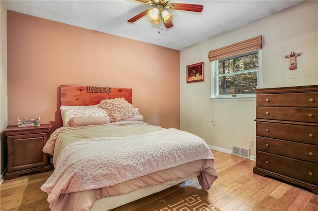 bedroom featuring baseboards, light wood-style flooring, visible vents, and a ceiling fan