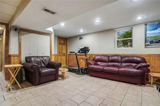 living area with wainscoting, wooden walls, and visible vents