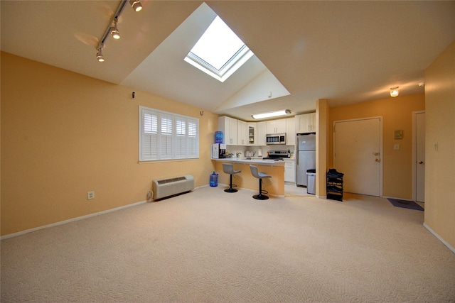 1337 Broadway Unit C22, Hewlett, NY 11557 - kitchen featuring stainless steel appliances, a peninsula, white cabinetry, light colored carpet, and vaulted ceiling with skylight