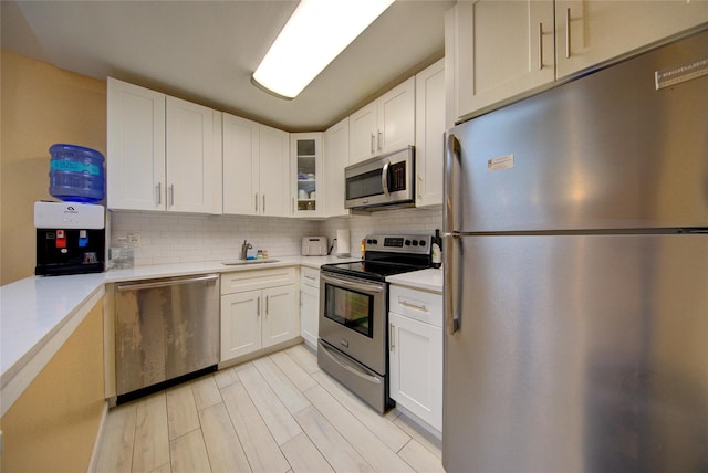 1337 Broadway Unit C22, Hewlett, NY 11557 - kitchen with decorative backsplash, glass insert cabinets, stainless steel appliances, and light countertops