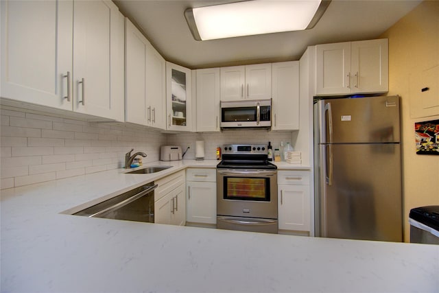 1337 Broadway Unit C22, Hewlett, NY 11557 - kitchen featuring decorative backsplash, white cabinetry, stainless steel appliances, and a sink