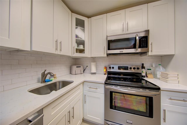1337 Broadway Unit C22, Hewlett, NY 11557 - kitchen featuring a sink, glass insert cabinets, tasteful backsplash, appliances with stainless steel finishes, and white cabinetry