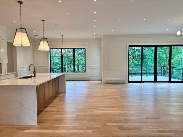 9 Ogrady Ct, Orangeburg, NY 10962 - kitchen with a decorative wall, a sink, open floor plan, a baseboard heating unit, and light wood-style flooring