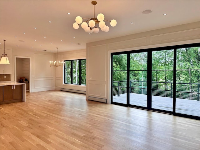 9 Ogrady Ct, Orangeburg, NY 10962 - unfurnished living room with a chandelier, a decorative wall, a baseboard heating unit, baseboard heating, and light wood-style floors