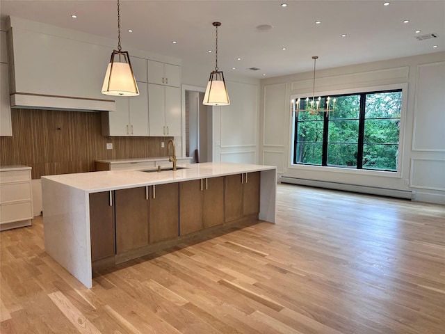 9 Ogrady Ct, Orangeburg, NY 10962 - kitchen with a decorative wall, a baseboard radiator, light wood-type flooring, a large island, and white cabinets