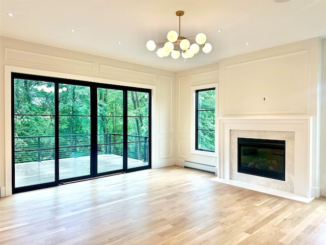9 Ogrady Ct, Orangeburg, NY 10962 - unfurnished living room featuring baseboard heating, a decorative wall, a chandelier, light wood-type flooring, and a high end fireplace