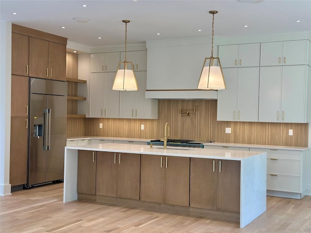 9 Ogrady Ct, Orangeburg, NY 10962 - kitchen featuring high end refrigerator, light countertops, open shelves, a center island with sink, and light wood finished floors