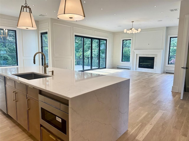 9 Ogrady Ct, Orangeburg, NY 10962 - kitchen with a sink, a decorative wall, open floor plan, an island with sink, and light wood-style floors