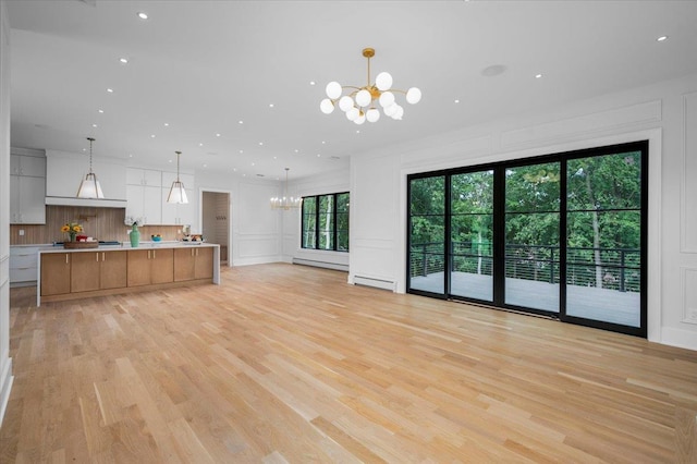 9 Ogrady Ct, Orangeburg, NY 10962 - unfurnished living room featuring a chandelier, a baseboard heating unit, light wood finished floors, a decorative wall, and recessed lighting