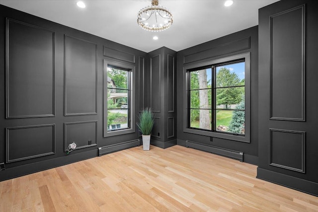 9 Ogrady Ct, Orangeburg, NY 10962 - empty room featuring a decorative wall, a baseboard heating unit, a chandelier, plenty of natural light, and wood finished floors