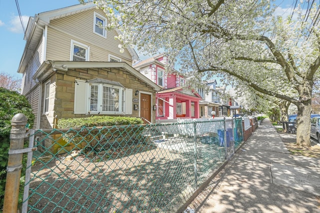 view of side of property featuring stone siding and a fenced front yard