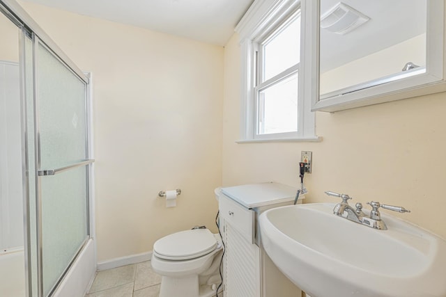 bathroom featuring a sink, bath / shower combo with glass door, toilet, tile patterned flooring, and visible vents